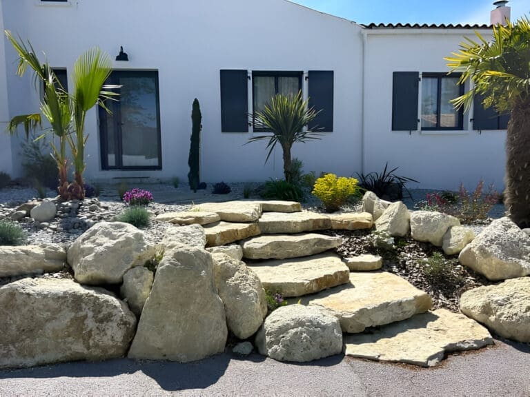 Vue d'un jardin paysager avec des rochers et des enrochements parfaitement intégrés, entourés de plantes.