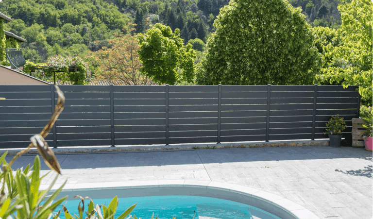 Clôture en aluminium moderne installée dans un jardin paysagé avec mobilier extérieur