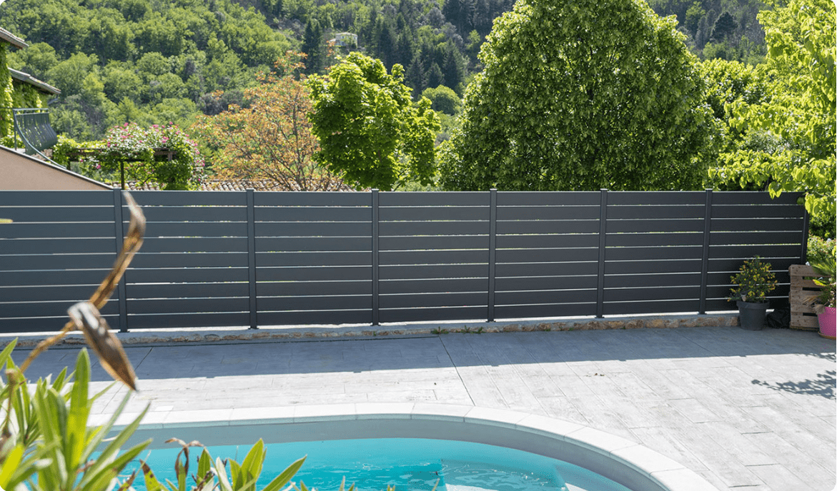 Clôture en aluminium moderne installée dans un jardin paysagé avec mobilier extérieur